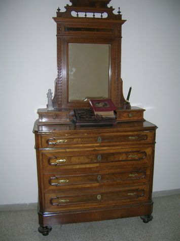 comò a 4 cassettoni e con specchiera incastonata nel legno.