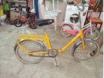 Bicicletta vintage gialla con telaio in metallo, sellino nero e portapacchi pos
